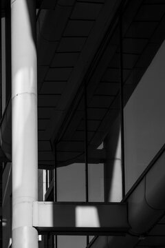 Modern industrial architecture reveals a facade with columns and structure where lines and shadow define an urban scene in sharp monochrome contrast