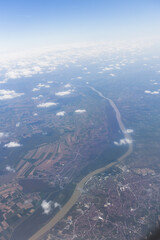 Fototapeta premium Aerial view of landscape with fields and river under scattered clouds.