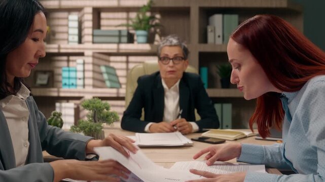 Three multiracial businesswomen team problem discussing bad business stats result throwing papers shocked middle-aged boss looking at irritated annoyed Asian Caucasian women arguing throw documents