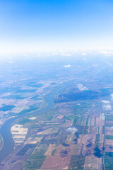 Aerial view from airplane window showing colorful patchwork of agricultural fields and rural landscape. 
