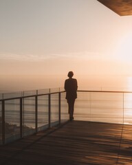 Fototapeta premium Silhouetted figure observing a serene ocean sunset from a modern elevated
