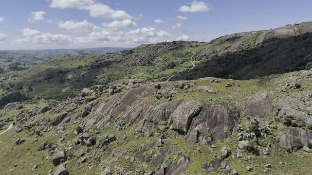 Drone orbits to the left in wide shot of middle of hiking trail on a sunny day at Sibebe Rock near Mbabane, Eswatini