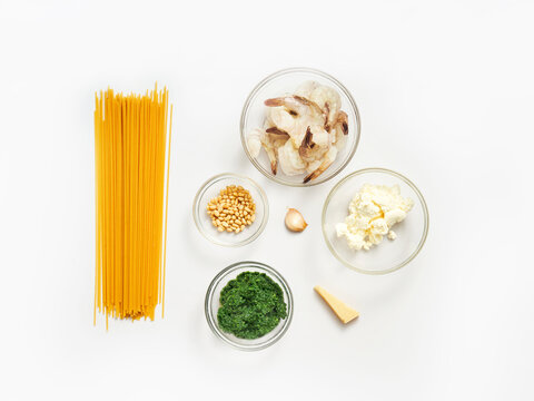 Shrimp, pasta, herbs, cheese, and other ingredients are arranged for meal preparation. This setup is ideal for recipe blogs, cooking classes, and food delivery services
