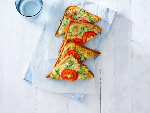 This image showcases cheesy vegetable toast garnished with fresh tomatoes on a light background. It is ideal for restaurant menus, food blogs, and advertising healthy breakfast options