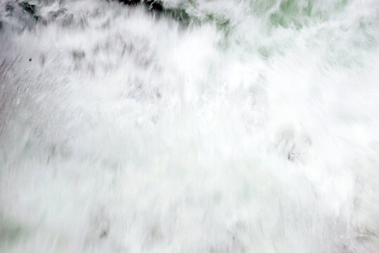 Background of defocuses powerful white exploding water rushing down a channel.