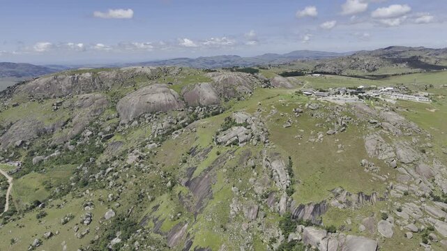 Drone lowers from wide shot just above resort to about halfway up the mountain on a sunny day at Sibebe Rock near Mbabane, Eswatini