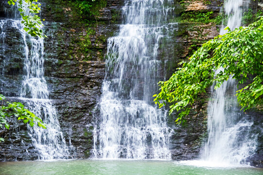 Zoomed in and a slow shutter speed captures delightful beauty of a unique triple waterfall flowing elegantly down a rock cliff in Arkansas. Bokeh.