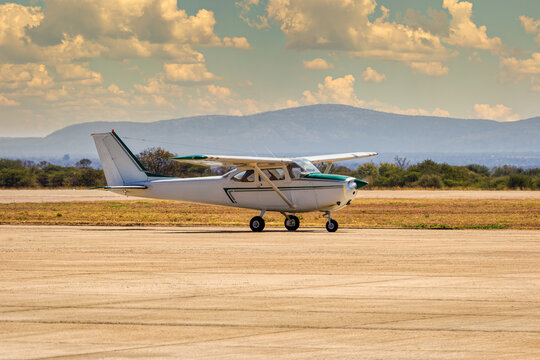 Private light aircraft taxiing on an airfield tarmac near mountains hilly landscape