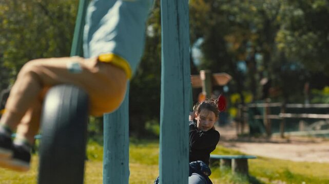 Happy children playing and swinging on tire swings at playground