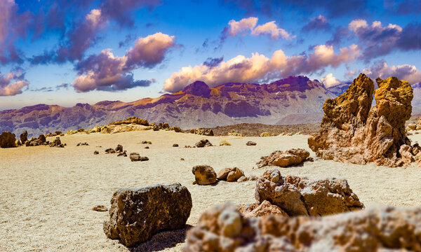 Paisaje volc&aacute;nico des&eacute;rtico con luz c&aacute;lida y monta&ntilde;as, que evoca aventura, aislamiento, belleza natural y un escenario espectacular. Terreno rocoso des&eacute;rtico con cantos rodados dispersos y monta&ntilde;as