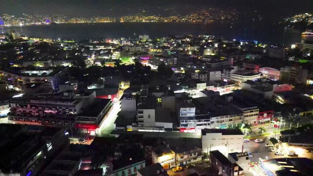 Vibrant Acapulco city at night, aerial drone view capturing New Year celebration. Illuminated cityscape with countless lights reflecting on the bay, showcasing the festive spirit of Mexico's famous re