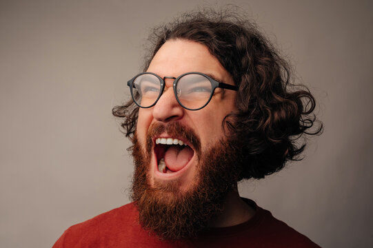 Laughing Bearded Man With Glasses Wide Open Mouth And Candid Roar, Curly Hair Flyaway, Expressive Eyes, Studio