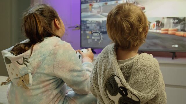 Joyful young brother and sister enjoy playing video games together at home. They hold controllers and smile while competing in a fun game, happy childhood moments in cozy living room 4K.