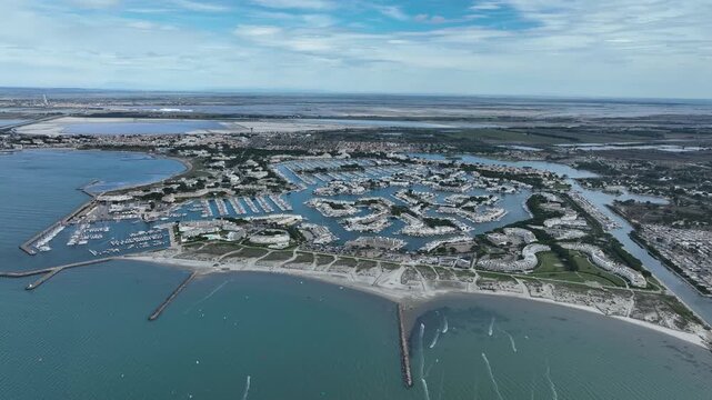 Aerial view of Grau-du-Roi France showing large marina with hundreds of boats sandy beach kitesurfers and coastal town under blue sky