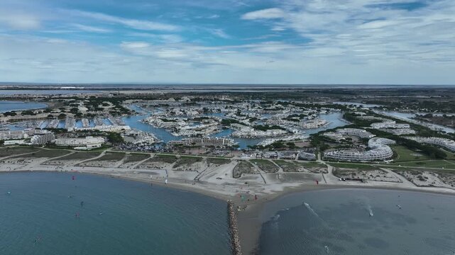 Aerial view of Grau-du-Roi France showing sandy beach kitesurfers sea harbor full of boats and modern coastal buildings under blue sky