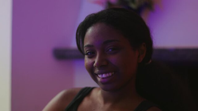 African American woman looking toward camera smiling warmly expressing happiness confidence and positive emotion in relaxed indoor home environment