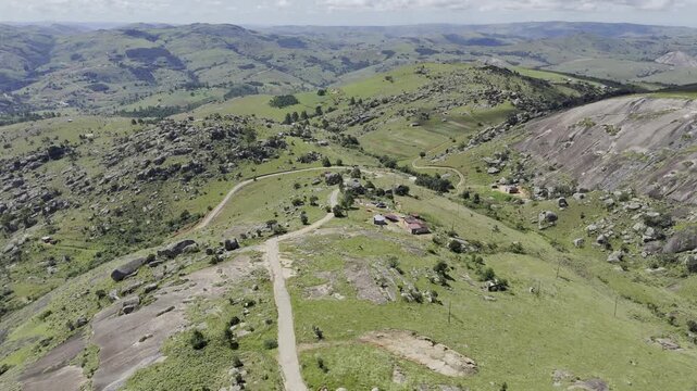 Drone flies north high over green rolling hills on a sunny day at Sibebe Rock near Mbabane, Eswatini