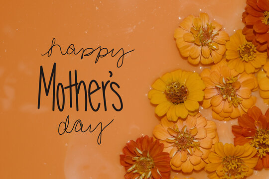 Happy Mothers Day greeting background with orange zinnia flowers as a flat lay banner for holiday.