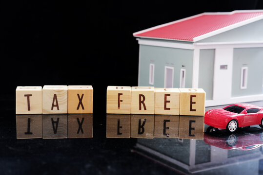 Miniature cars and miniature houses, with the words TAX FREE written on a dark background. Tax exemption with certain conditions.