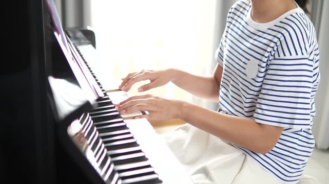 Close-up of young girl's fingers playing piano keys in a bright room for music education, talent, and artistic inspiration concept