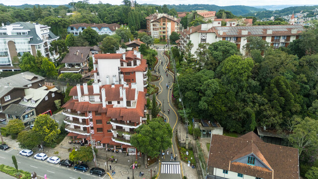 Vista a&eacute;rea da Rua Torta em Gramado com curvas sinuosas, vegeta&ccedil;&atilde;o e arquitetura ao redor destacando ponto tur&iacute;stico famoso da serra ga&uacute;cha