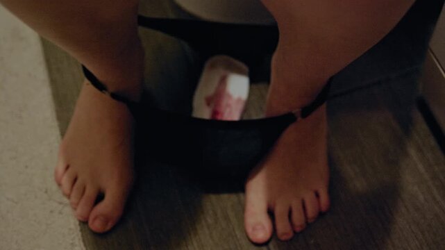 A woman checks her sanitary pad after removing it, with menstrual blood visible on the surface.