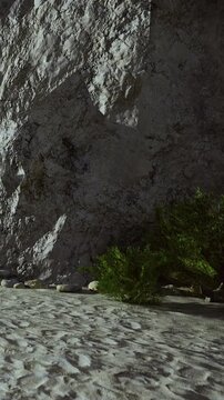 In a peaceful scene, textured rocks rise beside soft sandy ground, with gentle shadows dancing on the surface. This tranquil spot invites exploration and reflection amidst natures beauty.