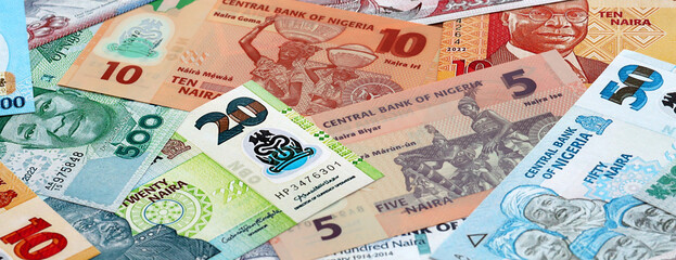 Fototapeta premium Nigerian naira money banknotes pile on table. Nigeria bills of NGN currency close up