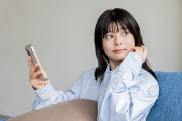 Fototapeta premium ソファに座ってスマホを操作する女性