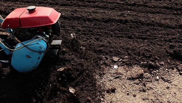A man plows the land with a motor cultivator in a field.