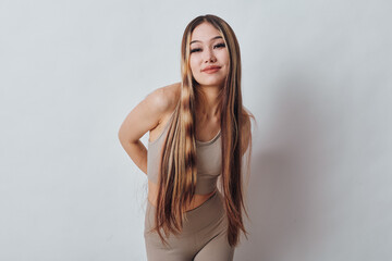 Naklejka premium Young woman with long braided hair posing and smiling in casual beige outfit against white background. Beautiful female model with relaxed posture and confident expression.
