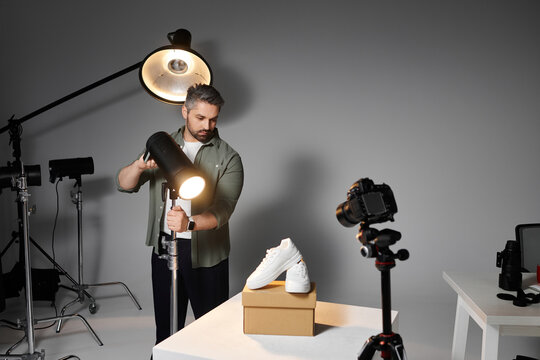 Professional photographer directing lighting for a product shoot in a creative studio space
