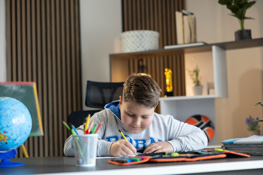 Young boy learning and doing homework at a desk in a modern home environment, focusing on his education