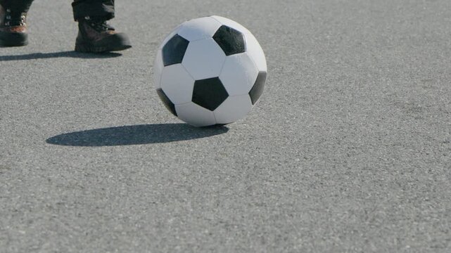 Kids practice football on a cold day with snow on the ground near a paved road and an adult supporting them