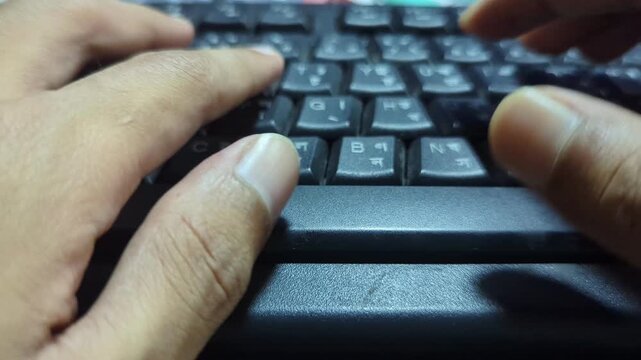 Hands typing fast on black computer keyboard with bengali characters in close up view providing digital input and data entry for professional business work or personal communication projects.