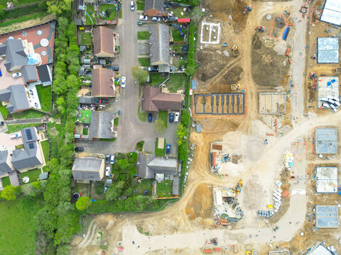 Drone UAV view of  a new housing development site in rural Britain. The foundations of the houses can be seen and the outline of the new road. Seen adjacent to existing houses.