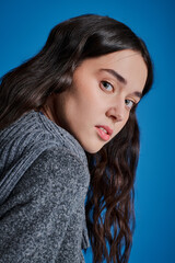 Naklejka premium Stylish woman with flowing hair showcases modern fashion against a vibrant blue backdrop