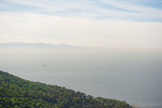 Calm sea horizon with distant ships and haze