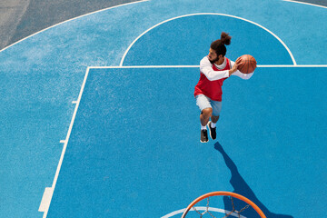 Dynamic basketball action on an outdoor court by a young African American man © LIGHTFIELD STUDIOS