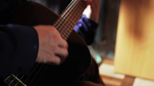 Close view of a hand playing guitar strings in a cozy room during a music practice session