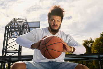 Young basketball player showcasing skills on an outdoor court with bright sky backdrop © LIGHTFIELD STUDIOS