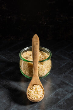 Jasmine rice in a glass jar with a wooden spoon on a dark surface 