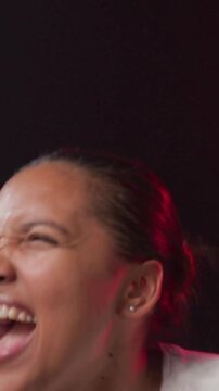 Vertical video: Cueing woman in striped white tee pumping arms shouting in studio under red rim