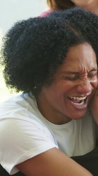 Vertical video: Hugging trio warmly on couch at home while left entering wearing red ringer tee