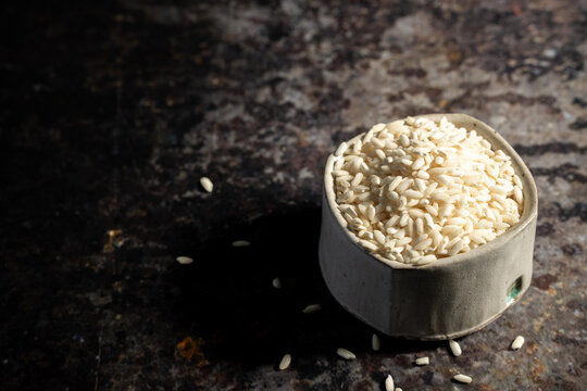 Arborio rice in a ceramic bowl on a dark surface 