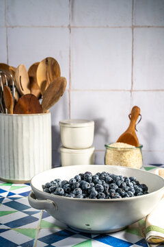 Blueberries in a ceramic colander on a tile countertop 