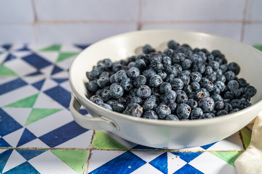 Blueberries in a ceramic colander on a tile countertop 