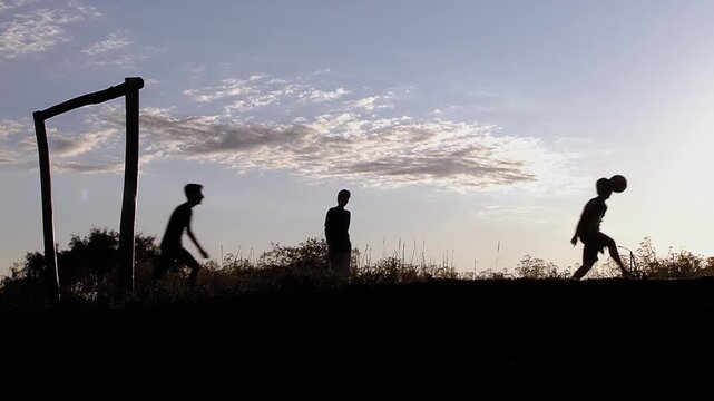 Silhouette Of Three Young Men Playing Soccer On Rural Landscape At Sunset In Argentina 