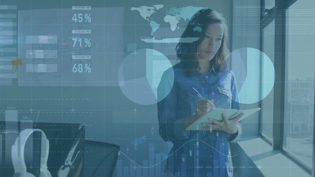 Female analyst standing at window taking notes, initiating business data overlays showing charts