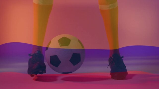 Male player training soccer dribbling, nudging ball right on pink floor, purple band crossing frame